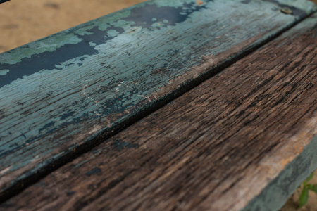 A wooden bench is placed outdoor in a park for years. Sunlight and rains are the cause that erode its coating and surface.の写真素材