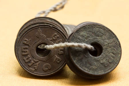 Thai ancient coins were minted with holes in the middle. An easy way to collect or carry the coins, is to string through those holes.の写真素材
