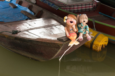 Two junior mermaids catching fishes on a boat, are having fun perhaps because of sneaking away from home.の写真素材