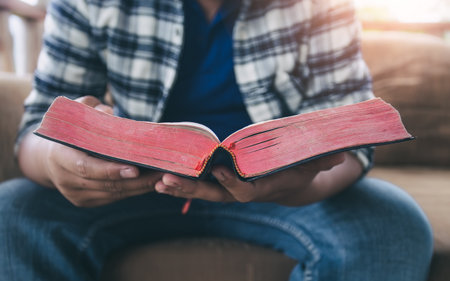 Close up Bible with a man reading on sofa at home. christian concept.の写真素材