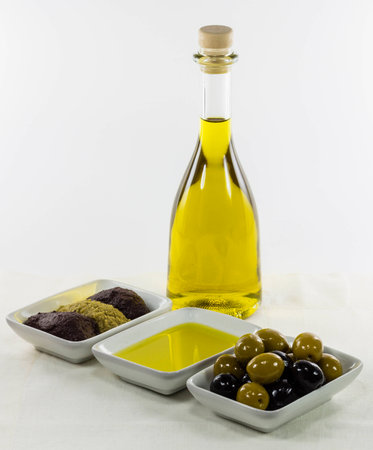 Extra virgin olive oil glass bottle and dished sample, plus black and green olives and olives pasteの写真素材