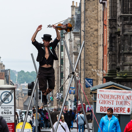 Edinburgh, Scotland - September 14, 2014: street performer walking on a rope while holding a violin in his hand. The High Street section of the Royal Mile is a preferred stage for street performances.のeditorial素材
