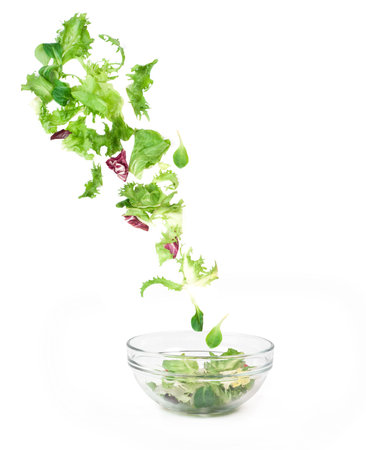 Fresh mixed vegetables falling into a bowl of saladの写真素材