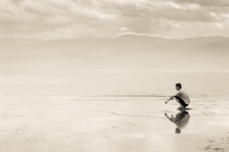 Qionghai sea, Xichang, Sichuan Province, China - May 17, 2013: A isolated fisherman waiting in the haze on the lake borders.のeditorial素材
