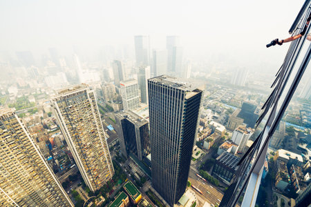 Man Taking Photo of the city in handheld haze from the window of a skyscraper, Chengdu, Sichuan Province, Chinaのeditorial素材