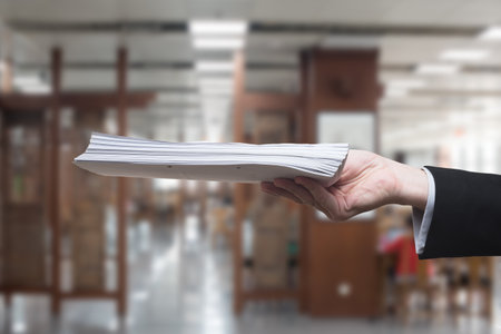 Hand of businessman holding a pile of papers in an office