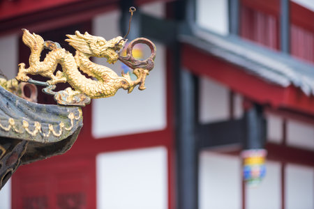 Golden colored dragon sculpture with a temple building in the background, Chengdu, Sichuan Province,...