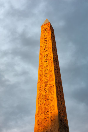 Concorde Obelisk in orange light from sunset against cloudy sky in Paris, Franceのeditorial素材