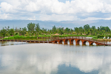 Lake with wooden bridge and mountains in the background in Chinaの写真素材