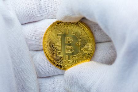 Hands with white gloves holding a golden bitcoinの写真素材