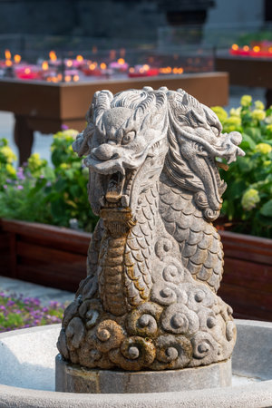 Dragon sculpture in a fountain in Daci buddhist temple roof against modern building in Chengdu, Chinaの写真素材