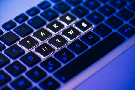 Fake news  on a backlit keyboard in a blue ambient lightの写真素材