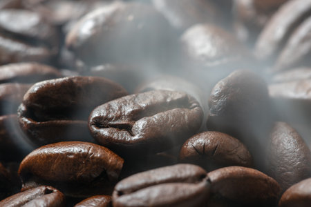 Heap of roasted coffee beans close-up with smoke