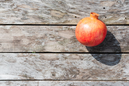 A pomegranate on a wooden table under sunlight