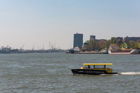 Rotterdam, Netherlands - April 18, 2019 : Water taxi speeding over the new Meuse river with city buildings in the backgroundのeditorial素材