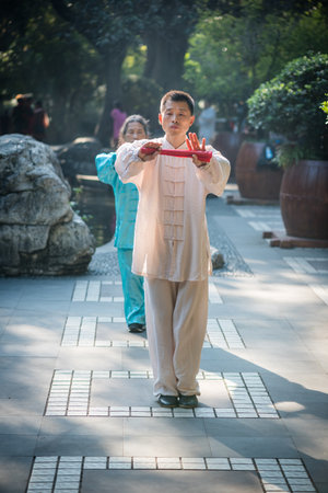 Chengdu, Sichuan province, China - Oct 31, 2018 : Man and woman practising Tai Chi with red fans in the morning in Peoples park.のeditorial素材