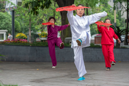 Chengdu, Sichuan province, China - May 2, 2016 : Three women practising Tai Chi with red fans in the streetのeditorial素材