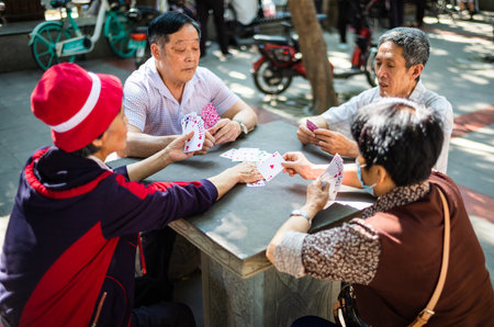 Chengdu, Sichuan province, China - May 29, 2022: Senior Chinese people playing cards outdoors in YuLin market on a sunny dayのeditorial素材