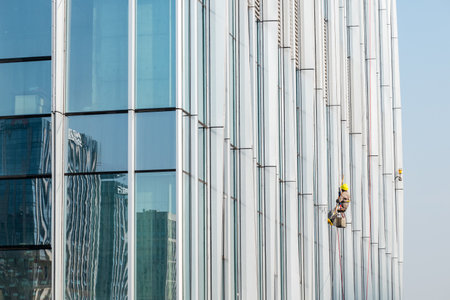 Chengdu, Sichuan province, China - Dec 21, 2022 : Worker cleaning skyscrapers facade windows on a...
