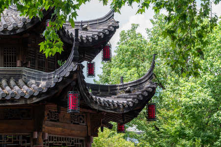 A classic Chinese architectural structure, characterized by its curved, tiled roofs and intricate wooden details. The building is adorned with red lanterns.の写真素材