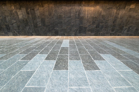A smooth, modern stone pavement stretches out, contrasting with a sleek stone wall in Chengdu, Sichuan. The polished stones create a sophisticated atmosphere in this urban setting.の写真素材