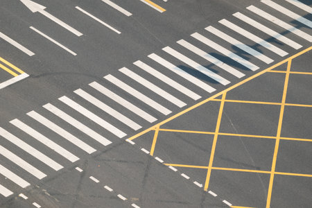 The streets reveal a complex pattern of road markings. White crosswalks and yellow lines create a...
