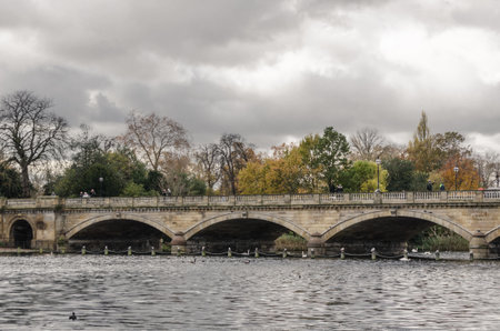An old stone bridge crossing a lake inside a forest on a cloudy dayの写真素材