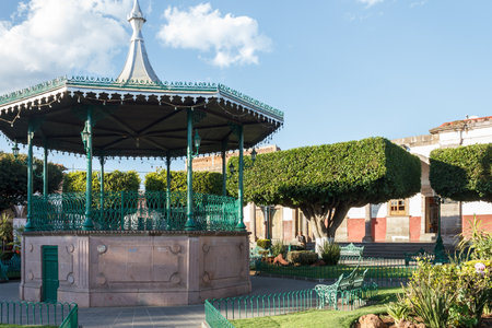 A gazebo at a plaza with  trees cut into square shapes in Quiroga, Michoacan, Mexicoの写真素材