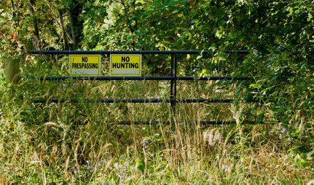 Steel gate with warning signs in the foliageの写真素材