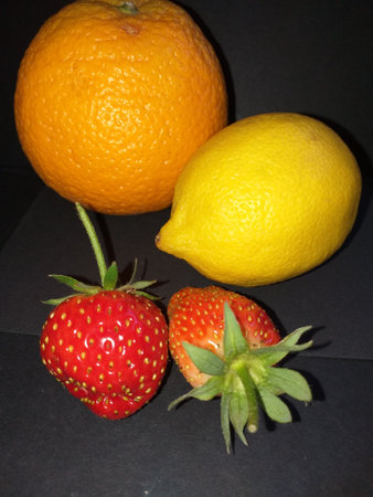 Fruits of the forest, two small strawberries from a container in the garden and an orange and lemonの写真素材