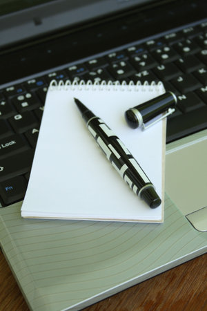 Pen on notebook and laptop computer.