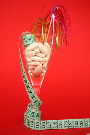 Glass filled with diet pills on a red background.の写真素材