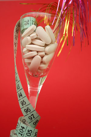 Glass filled with diet pills on a red background.の写真素材