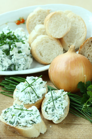 Baguette slices with spread from chives on cutting board の写真素材