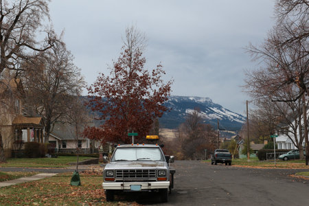 A chilly crisp fall day in a small town in US. Looking down a street with an old truck, fall colored trees, and the mountain with snow creeping down.の写真素材