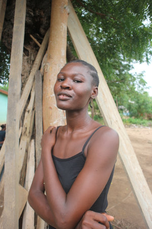 Young african american woman in black dress standing under a tree.の写真素材
