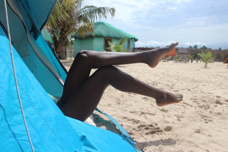 African woman's legs sticking out of a tent in the morningの写真素材