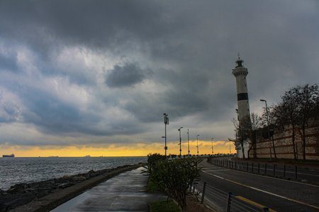Lighthouse on the seashore in the evening with dark cloudsの写真素材