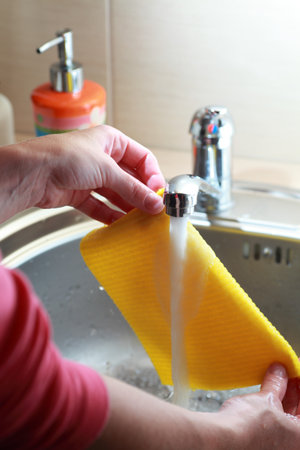 yellow cloth and hands under running water の写真素材