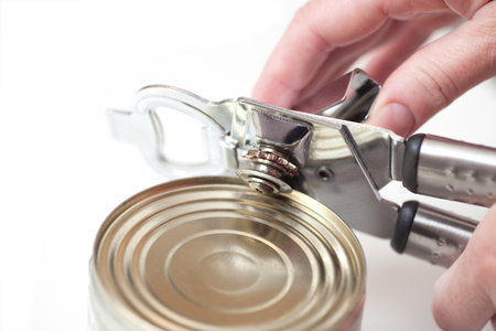 hand Tin opener opening a can of food isolated on white の写真素材