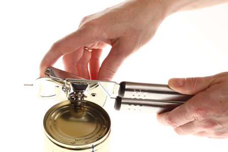 Hand and Tin opener opening a can of food isolated on white の写真素材