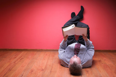 men lying in the floor on red wall backgroundの写真素材