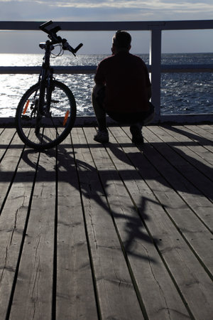 man bike at the pier, jetty in morning seaの写真素材