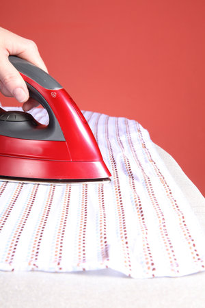 household chores - red iron in hand and white shirt 
の写真素材