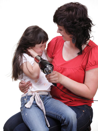 woman and Little girl dries hair, daughter isolated on whiteの写真素材