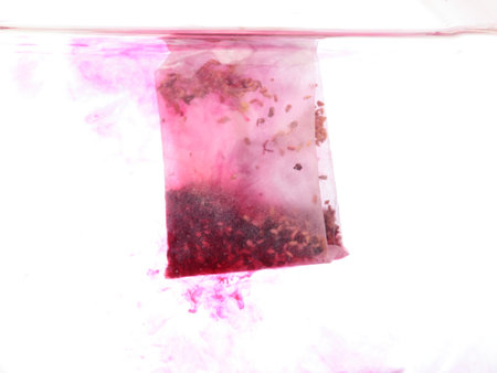 red Teabag in hot water in white backgroundの写真素材