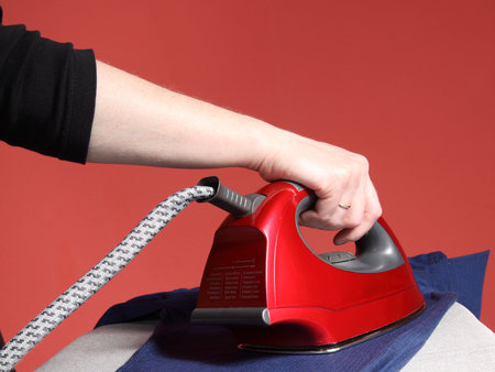 household chores - red iron in hand and navy blue shirt 
の写真素材