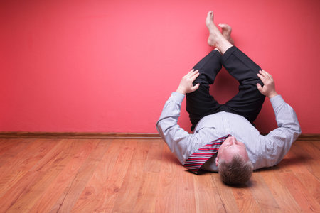 men lying in the floor on red wall backgroundの写真素材