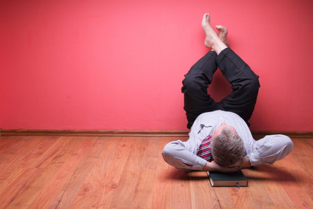 men lying in the floor on red wall backgroundの写真素材