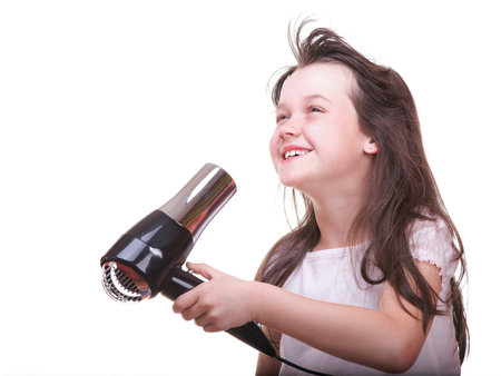 Pretty girl drying her hair hairdryer isolated on whiteの写真素材